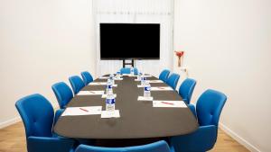 uma sala de conferências com uma mesa longa e cadeiras azuis em Séjours & Affaires Paris Bagnolet em Bagnolet