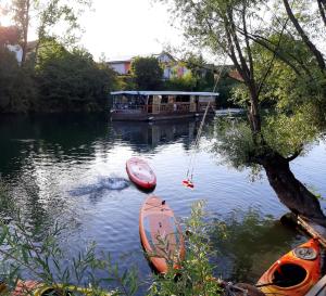 two canoes sitting in the water next to a boat at River Houses Ljubljanica in Ljubljana