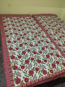 een quilt met rode bloemen op een bed bij Sri Viswanatham guest House in Varanasi
