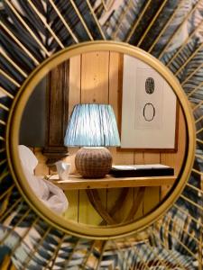 een spiegel met een lamp op een tafel bij Hôtel Le Caillebotis in Cap-Ferret