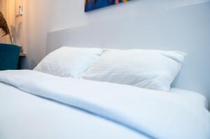 łóżko z białą pościelą i poduszkami w pokoju w obiekcie Daisy resort w Nowym Sadzie