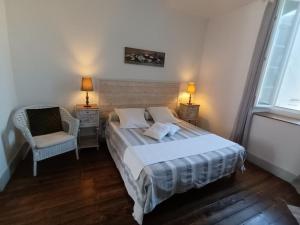 1 dormitorio con 1 cama, 1 silla y 2 lámparas en Le Clos Fleuri, en Caumont