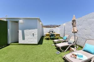 eine Terrasse mit Stühlen, einem Sonnenschirm und einem Tisch in der Unterkunft Apartamento Deluxe en Cruce de Arinaga GRANEL in Cruce de Arinaga