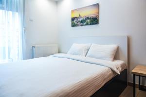 a bedroom with a white bed with a picture on the wall at Daisy resort in Novi Sad