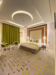 a bedroom with a large bed and a green curtain at HOTEL ALFAW PLAZA in Sharurah