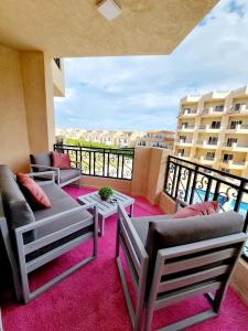 a living room with couches and tables on a balcony at Selena Bay Hurghada - Pink Apartment in Hurghada