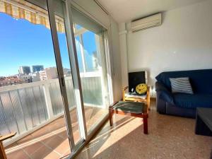 a living room with a blue couch and a large window at Big Family Terrassa Parking and noise free in Terrassa