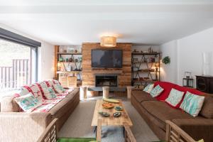 a living room with two couches and a television at La Désirade Incroyable lodge typique dans les Vosges du Sud in Linthal