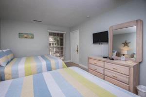 ein Schlafzimmer mit einem Bett und eine Kommode mit einem Spiegel in der Unterkunft Litchfield Beach & Golf Resort in Pawleys Island