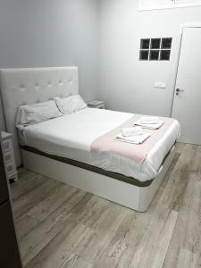 um quarto com uma cama com lençóis brancos e piso em madeira em Exyca Tetuán em Madri