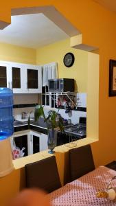 eine Küche mit einem Tisch und einer Uhr an der Wand in der Unterkunft Petite Lounge in Los Paredones