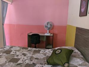 1 dormitorio con 1 cama y escritorio con ventilador en Kitnet Recanto do Bem-te-vi, en Jacaraípe