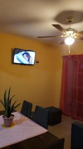 ein Esszimmer mit einem Tisch und einem TV an der Wand in der Unterkunft Petite Lounge in Los Paredones