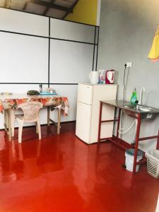 een keuken met een tafel en een tafel en een koelkast bij Railway Hostel in Matara