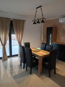 comedor con mesa de madera y sillas negras en Apartman SARA, en Vršac
