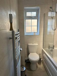 a bathroom with a toilet and a tub and a window at Atlantic House, Walking Distance to Cardiff Bay and City Centre with Parking in Cardiff