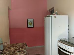 cocina con nevera blanca y pared rosa en Kitnet Recanto do Bem-te-vi, en Jacaraípe