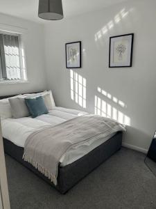 łóżko w sypialni z białymi ścianami i oknami w obiekcie Atlantic House, Walking Distance to Cardiff Bay and City Centre with Parking w Cardiff