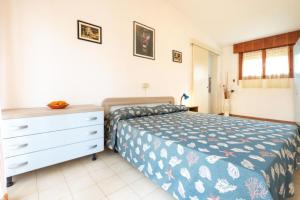 a bedroom with a bed and a dresser at Cozy and welcoming house with private garden in Lignano Sabbiadoro
