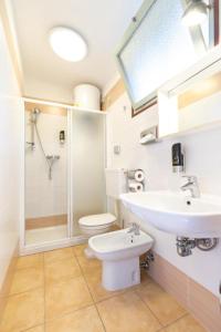 uma casa de banho com um lavatório, um WC e um chuveiro em Cozy and welcoming house with private garden em Lignano Sabbiadoro