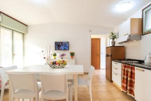 a kitchen and dining room with a white table and chairs at Cozy and welcoming house with private garden in Lignano Sabbiadoro
