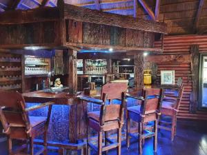 a dining room with wooden walls and a bar with chairs at 4 Fish Eagle Lodge in Sasolburg