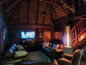 a living room with leather couches and a television at 4 Fish Eagle Lodge in Sasolburg