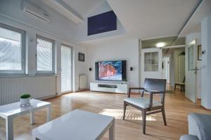 ein Wohnzimmer mit einem Stuhl und einem TV an der Wand in der Unterkunft Matic Spacious Modern Apartment in Ljubljana