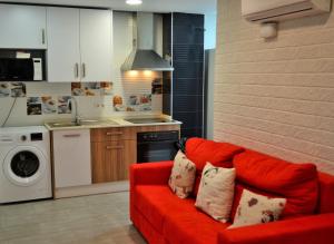 ein Wohnzimmer mit einer roten Couch in der Küche in der Unterkunft Apartamentos Garage Centro in Málaga