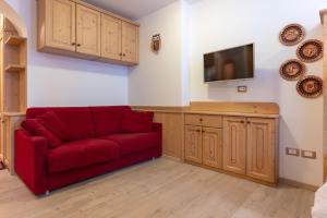 un soggiorno con divano rosso e TV di Bilo al Piccolo Gufo ad Andalo