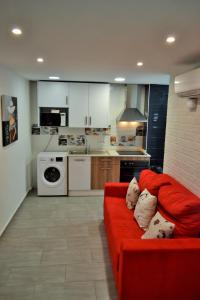 ein Wohnzimmer mit einem roten Sofa und einer Küche in der Unterkunft Apartamentos Garage Centro in Málaga