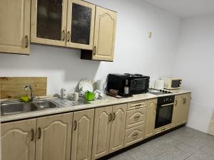 una cucina con armadi in legno, lavandino e forno a microonde di Márti a Odoreu