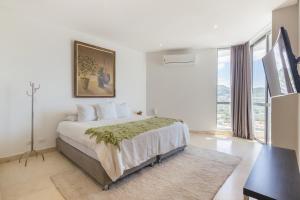 a white bedroom with a bed and a large window at Grand Marina Suites Santa Marta in Santa Marta