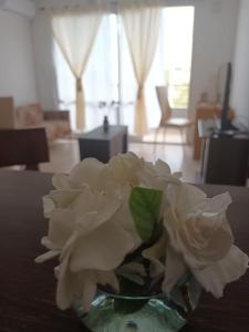 un vase rempli de roses blanches assis sur une table dans l'établissement DEPTO 2 Y 62 CON COCHERA PROPIA, à La Plata