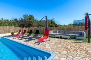 uma piscina com cadeiras, um sofá e um guarda-sol em Ana em Ližnjan