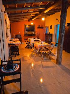 a room with tables and chairs and a television at Canto do Rio Pousada in Vargem Bonita