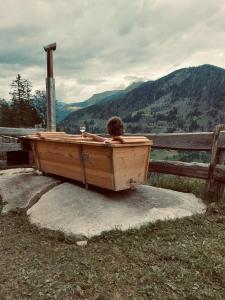 a person is sitting in a wooden bath tub at Untere Roner Kasa in Mörtschach