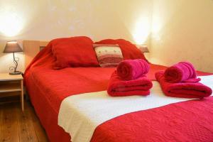 Una cama roja con toallas encima. en Gîte de la Bastide - Typique de Mirepoix en Mirepoix