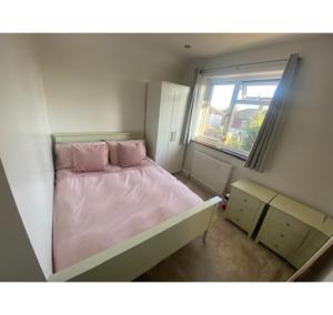 ein kleines Schlafzimmer mit einem rosa Bett und einem Fenster in der Unterkunft Hove House, 15 mins to seafront, free parking certain times in Hove