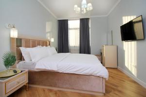 a bedroom with a large white bed and a flat screen tv at Modern, Spacious and Elegant Apt in Almaty