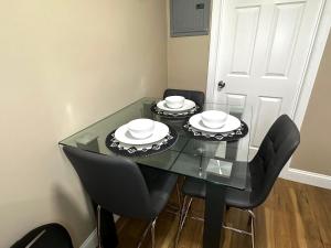a glass table with black chairs and white plates on it at Cozy Brockton Nook in Brockton