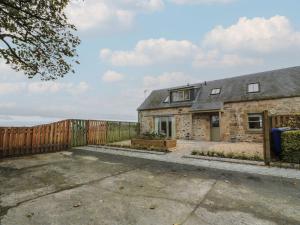 een oud stenen huis met een houten hek bij Thorneydyke Cottage in Stirling