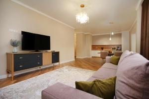 a living room with a couch and a flat screen tv at Modern, Spacious and Elegant Apt in Almaty