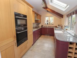 a kitchen with wooden cabinets and a black appliance at Badgers in Sedbergh
