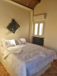 1 cama blanca en un dormitorio con ventana en safari desert en Bawiti