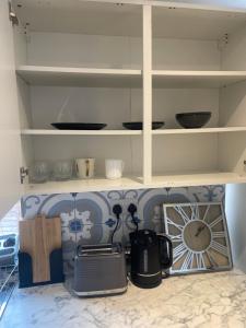 a kitchen with white shelves and a counter top at One Bedroom Annex with Private Entrance in Morden