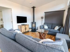 a living room with two couches and a flat screen tv at Osprey View Lodge & Hot Tub in Aberfeldy
