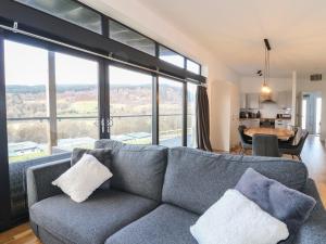 a living room with a couch and a large window at Osprey View Lodge & Hot Tub in Aberfeldy