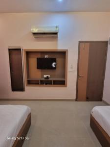 a room with two beds and a flat screen tv at Green Villa - Luxury Rooms at peaceful location -200 mtrs away from Bus Stand -500 mtrs from Udaipur Railway Station - Family Suites w Kitchen also available in Udaipur