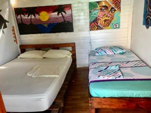2 camas en una habitación con un cuadro en la pared en Alojamiento playa blanca Barú. InHousecaribe, en Playa Blanca
